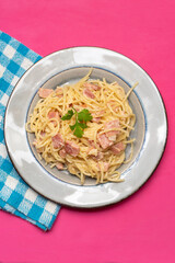 creamy spaghetti pasta with ham on pink background