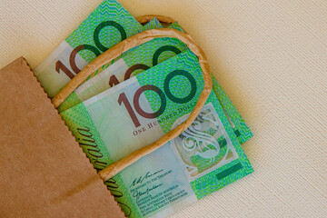 Australian one hundred dollar notes in a brown paper bag.