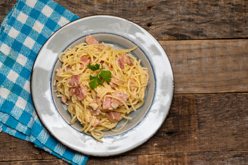 creamy spaghetti pasta with ham on wooden background