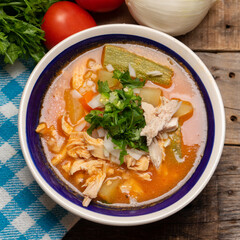Mexican chicken soup with vegetables and rice on wooden background