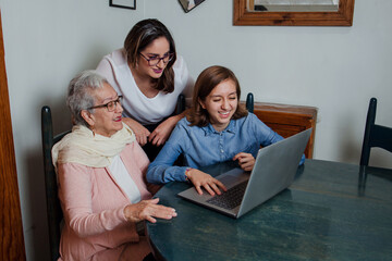 Hispanic Grandmother, daughter and granddaughter sitting with computer or laptop in home in Mexico