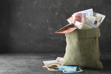 Sack full of money on grey table. Space for text