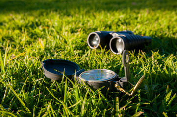 compass in foreground with binoculars and a mask in the green grass