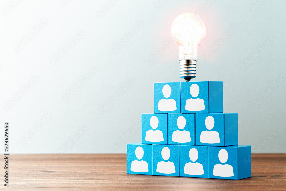 Poster teamwork and creativity. lightbulb and stacked blue blocks with person icons on wood table.