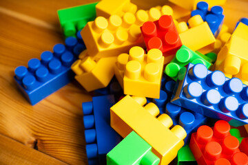 Fototapeta premium Plastic toy blocks different colours on the wooden table. Selective focus. Shallow depth of field. 