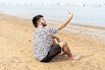 Adolescente con mascarilla haciéndose fotos selfies en la orilla del mar en la playa