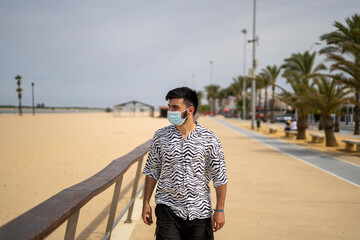 Hombre Joven con mascarilla paseando por el paseo marítimo disfrutando del mar y la playa
