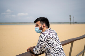 Hombre Joven con mascarilla paseando por el paseo marítimo disfrutando del mar y la playa