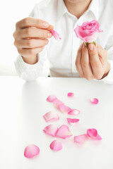 man pulling petals from rose
