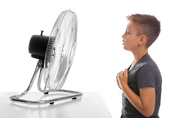 Little boy enjoying air flow from fan on white background. Summer heat