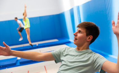 Close up portrait of teenager boy training jumping movements during trampoline workout