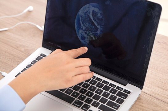 Finger with earth picture on laptop screen