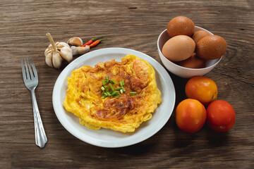 Omelet with tomato in white plate on wooden table background