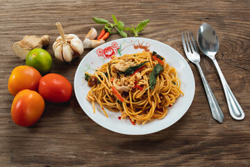 Stir fried spicy spaghetti with pork on wooden table background