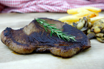 Rump steak with chips and mushroom on a wooden board