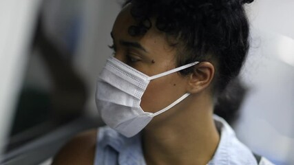 Young woman riding metro wearing surgical mask. student or worker commuting in subway looking out window - Powered by Adobe