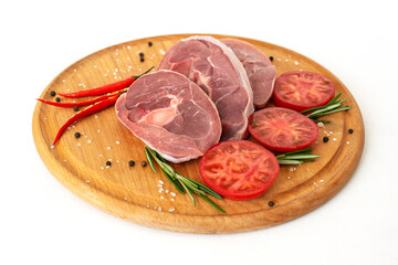 pieces of raw turkey meat, chopped leg steak, portioned barbecue pieces, on wooden board with rosemary, tomatoes and red hot pepper. isolate