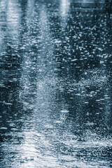 city street during summer rain. flooded asphalt road with multiple splashes of raindrops