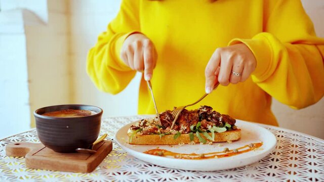 Close up woman eating sandwich with chicken and a hot coffee in caf&egrave;.4K video 
