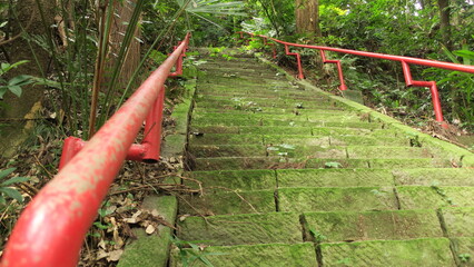 崩れかけた赤い手すりのある急な石階段