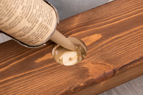 The mounting glue is extruded into a drilled round hole in a wooden board