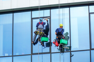 Two climbers wash windows in a high-rise building.
