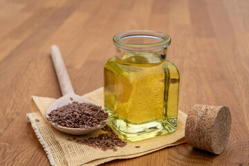 Flex seed oil in jar and dry flex seed on wood spoon on the table.