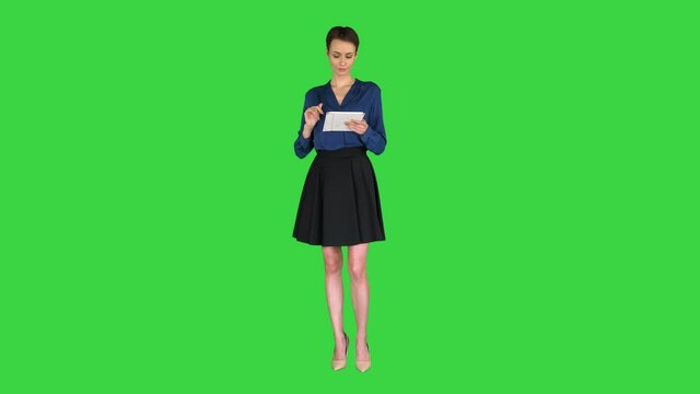 Businesswoman isolated swiping the tablet presenting something on a Green Screen, Chroma Key.