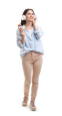 Fototapeta premium Young woman with bottle of water listening to music on white background