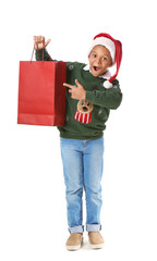 Cute African-American boy in Santa hat and with shopping bag on white background