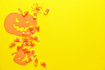 Tasty candies and paper pumpkins for Halloween on color background