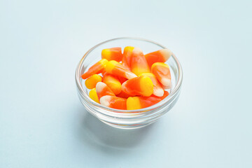 Tasty candies for Halloween in bowl on color background