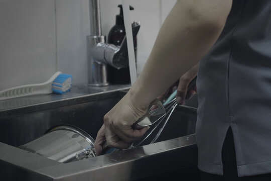 Closeup Of Female Hands Washing Dishes On Commercial Kitchen. Unrecognizable Female Standing At The Sink In The Kitchen And Wash Kitchen Utensil