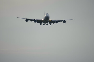 4 engine jumbo jet plane landing. Jet airplane descending before landing in airport at cloudy morning