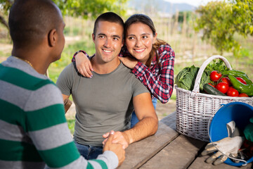 Cheerful couple of gardeners friendly talking to neighbor during break in work in spring garden