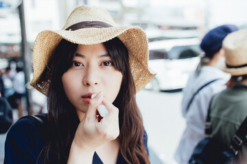 リップクリームを塗る麦わら帽子の女性