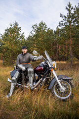 A medieval warrior in armor sits on a motorcycle with a sword in his hands on the background of the forest. Knight biker concept.