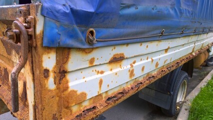 Sheet metal corrosion of old truck body. Rusty messy surface. Damaged grunge texture from road salt. Rust background. Protection and painting auto in winter. Professional paintwork. Car bodywork.