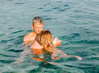 Grandfather teaching toddler girl swimming in sea