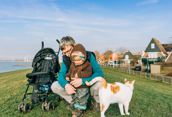 Toddler with grandfather and cat on dyke