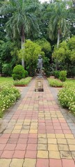 A beautiful path of garden surrounded by white flowers with statue of hunting boy at focus clicked in morning