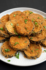 Homemade Garlic Parmesan Baked Eggplant on a plate on a black background, side view. Close-up.