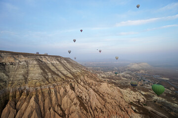 Colorful hot air balloon ride and tour in Goreme valley, semi-arid region in central Turkey known for its distinctive fairy chimneys, tall, cone-shaped rock formation- Cappadocia, Turkey