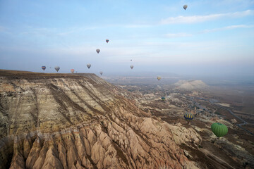 Colorful hot air balloon ride and tour in Goreme valley, semi-arid region in central Turkey known for its distinctive fairy chimneys, tall, cone-shaped rock formation- Cappadocia, Turkey