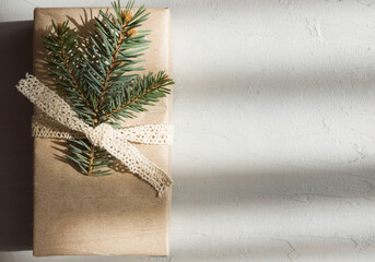 A rectangular box in a paper package is decorated with a spruce twig. Christmas gift in a...