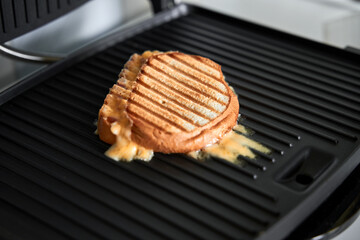 cooking panini with melted cheese on grill with golden crust