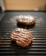 two ground pork burger patties on electric grill ready to eat. copy space for design mockup. fried meat product