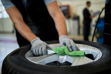 Close-up of a mechanic cleaning repaired car tire with a cloth.