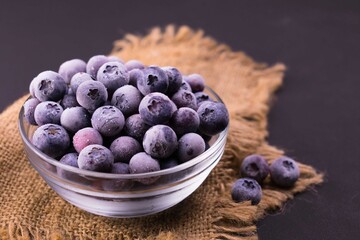 
Frozen blueberries in a transparent glass bowl.
Close-up.