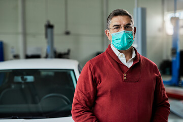 Fototapeta na wymiar Portrait of mid adult man with protective face mask in auto repair shop.